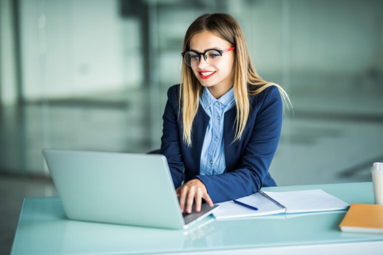 Smiling young businesswoman typing on laptop in the office